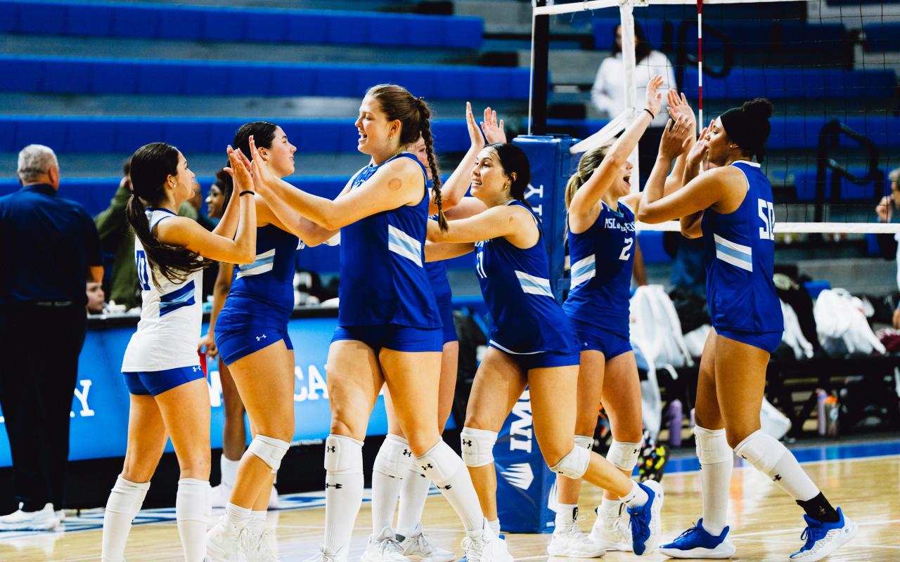 An IMG women's volleyball team celebrating courtside